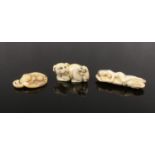 Three Japanese ivory netsukes. Carved in the form of two dogs, a toadstool with a snail and a