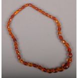 A string of graduated faceted amber beads. 25cm long.