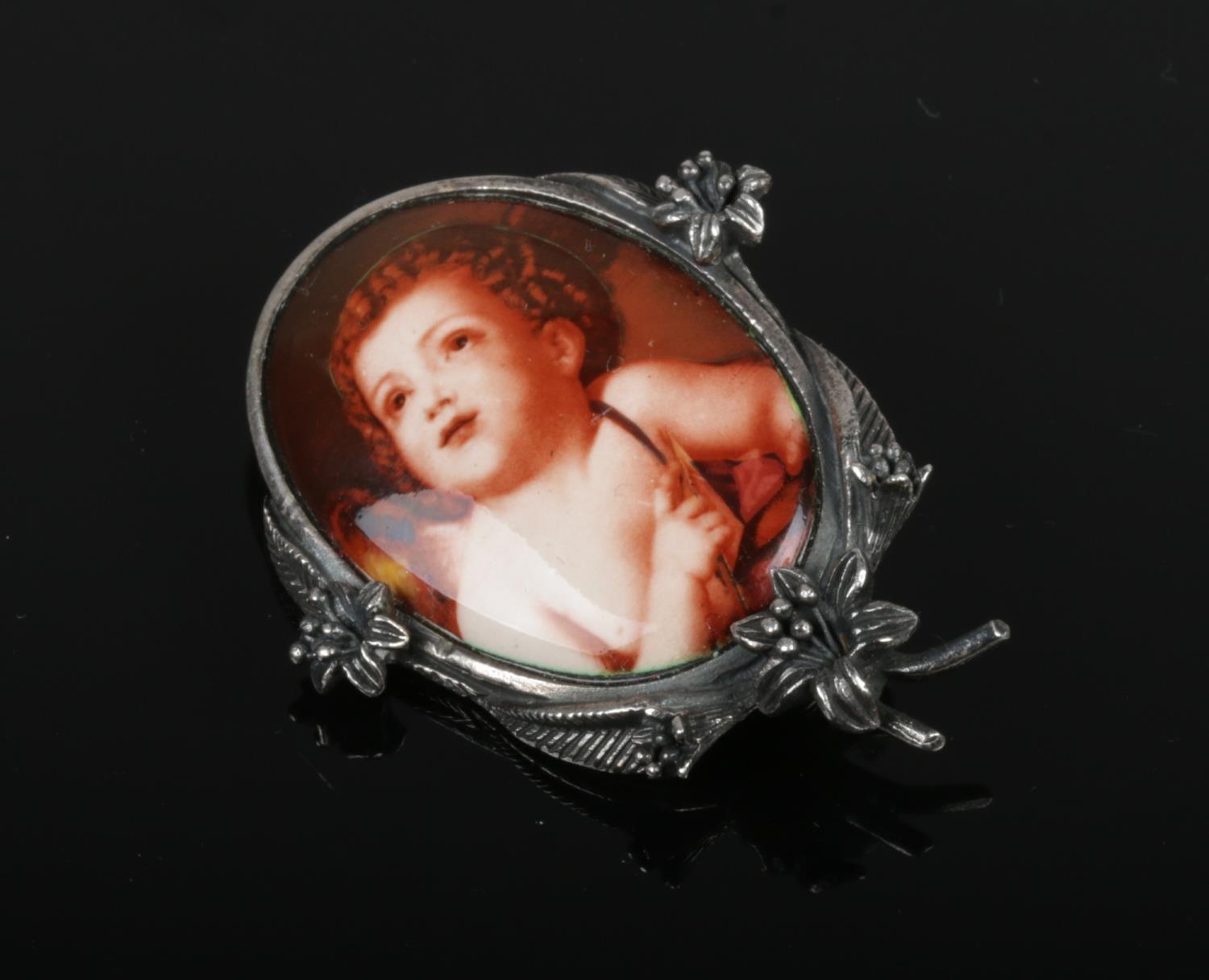 A sterling silver mounted brooch with ovoid enamel plaque decorated with a cherub.