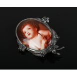 A sterling silver mounted brooch with ovoid enamel plaque decorated with a cherub.