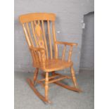 A modern pine slat back kitchen rocking chair.