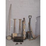 A collection of tools including pick axe, post spade, drain rods and ladle etc.