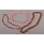 Two amber bead necklaces, one with silver clasp, along with a coral coloured bead necklace.