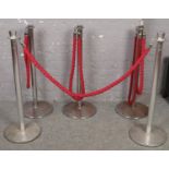 Two sets of chrome and red rope stanchion barriers.