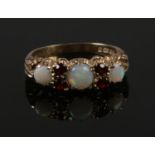 A 9ct gold, opal and garnet ring with scroll formed shank. Size L.