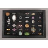 A display case with contents of 36 white and yellow metal dress rings.