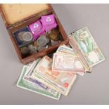 A wooden box with contents of British pre decimal and world coins and banknotes, to include