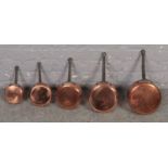 A set of five graduating copper pans with iron hooped handles