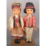 A pair of European dolls raised on wooden plinth.