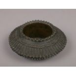A West African bronze bangle later converted to a dish. Cast with stylized bands, 13cm diameter.