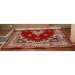 A large red ground wool carpet with central medallion design.