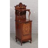 An Edwardian mahogany coal perdonium. With carved scroll pediment, mirrored back, having marquetry