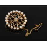 A 14ct gold, solitaire diamond and seed pearl open fret roundel brooch, 6.9 grams, 28mm wide.