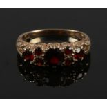 A 9ct gold and seven stone garnet ring with scroll formed shank. Size N.