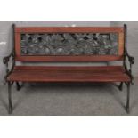 A wood and cast iron garden bench with floral back decoration.