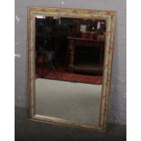 A wooden floral decorated wall mirror, with bevelled glass (74cm x 106cm)