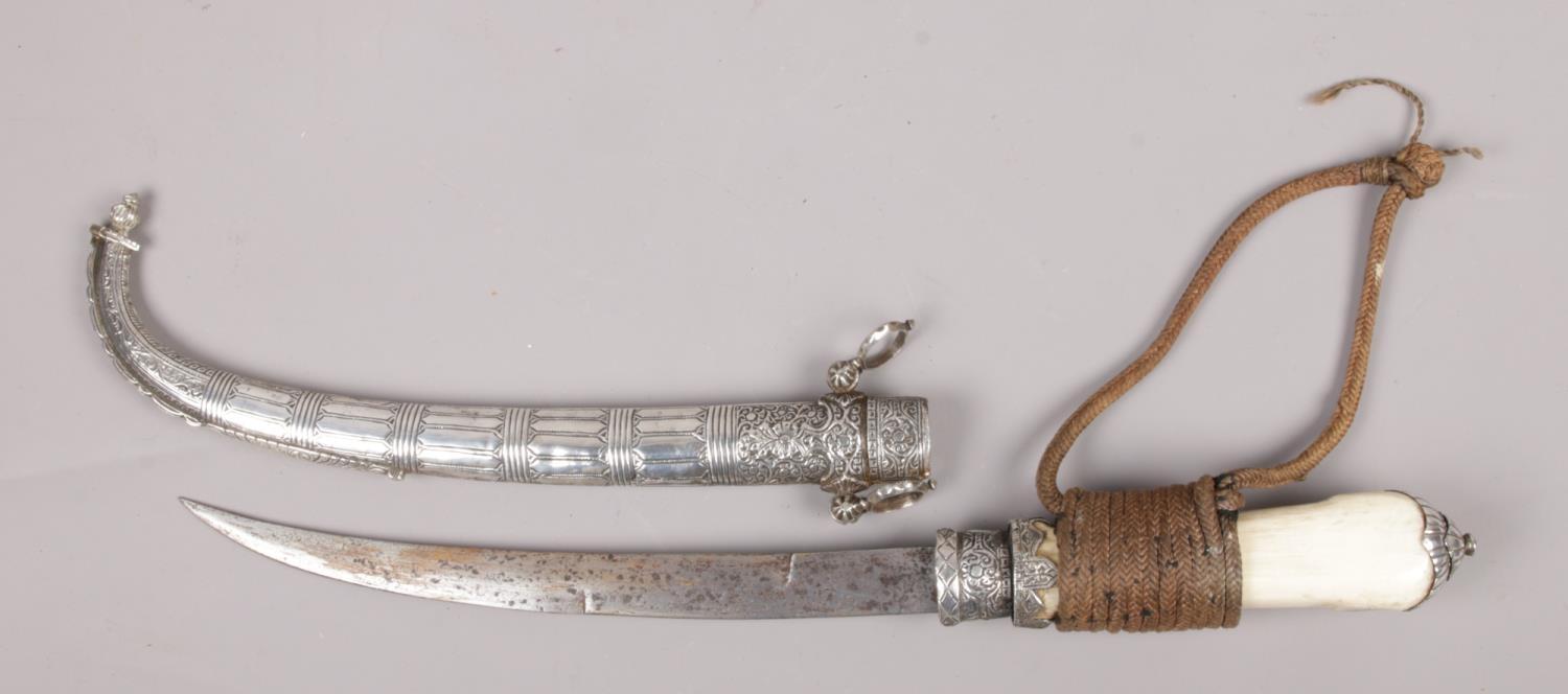 An Eastern bone handle dagger, with white metal mounts and scabbard.