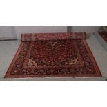 A large red ground wool rug, with central medallion design. (312cm x 205cm).