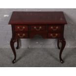 A modern mahogany lowboy, raised on cabriole supports and having brass handles.