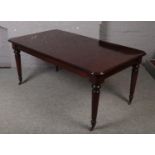 A mahogany extending dining table raised on reeded tapering supports, with extra leaf.
