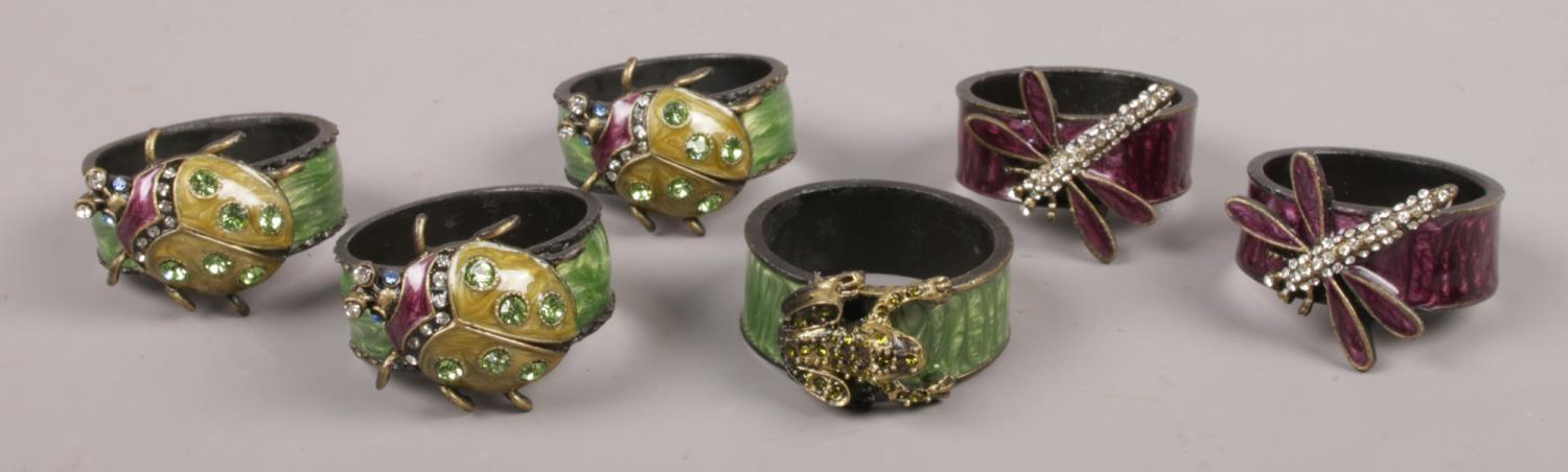 Six enamelled serviette rings, five decorated with paste set insects, the other with a frog.