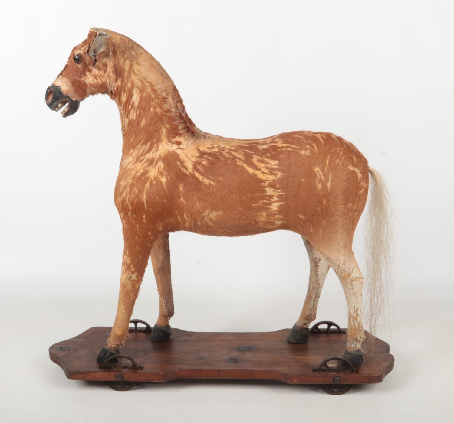 A child's 19th century toy pull along horse. With pony hide, raised on a pine plinth with metal