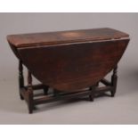 A George II oak gateleg dining table of pegged construction with single drawer and raised on