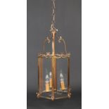 A hexagonal brass and glass three branch hall lantern. With double scrolling pediment and cast