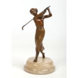 An Art Deco cold painted spelter figure formed as a female golfer mid swing and raised on an