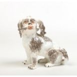 A Meissen style model of a Bolognese hound, 16cm. Two legs with repair.
