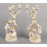 A superb pair of Royal Worcester Hadley style figural three branch candelabra. Each modelled as a
