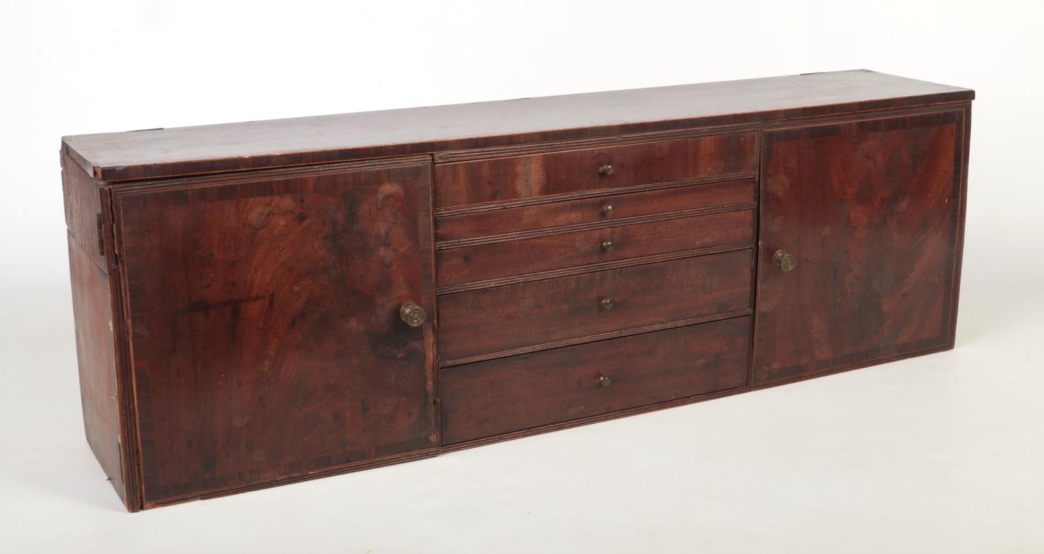 A Regency mahogany desktop bank of drawers flanked by a pair of cupboards. Crossbanded and with