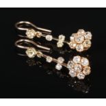 A pair of gold and diamond cluster drop earrings. Each formed from a seven stone daisy cluster