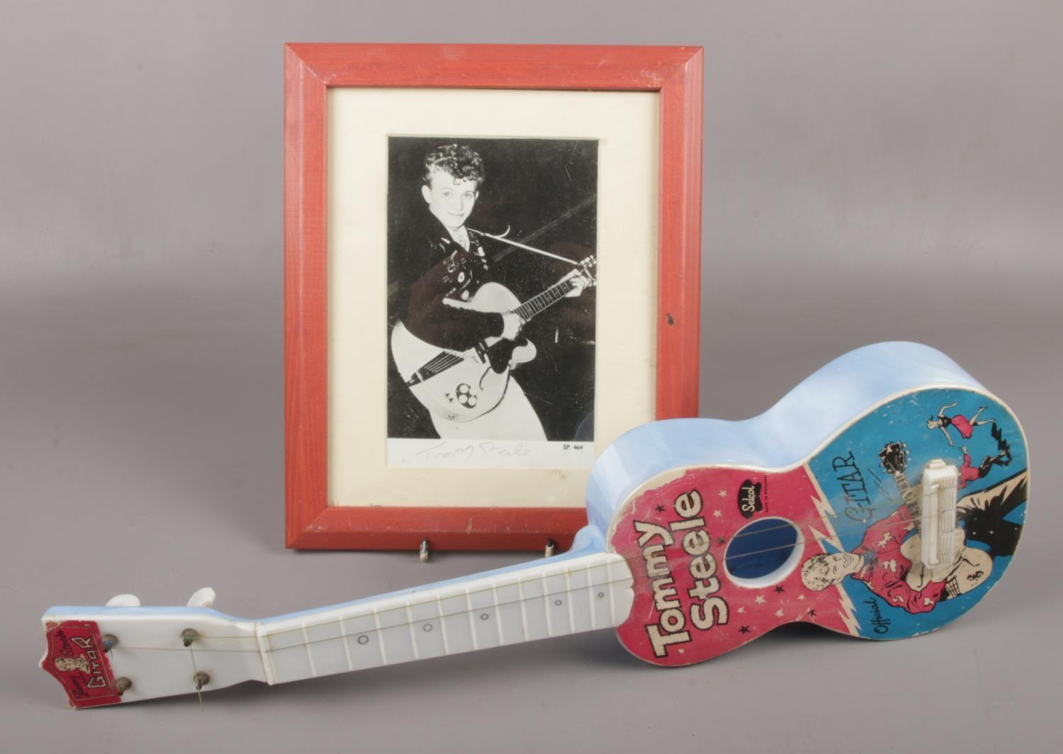 A Selco Tommy Steele plastic guitar, along with a framed autographed photograph.