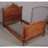 An ornate carved light oak French double bed frame.