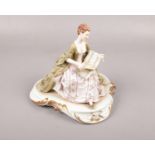 Capo Di Monte figure of a seated lady, reading sheet music. Signed but indistinct. Crack to the