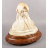 An alabaster bust of the Virgin Mary, raised on wooden plinth. (Total height 38cm).