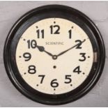 A circular Scientific wall clock with enamel dial. Missing glass.