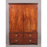A George III figured mahogany linen press raised on a three drawer base. With oak carcass, doric