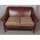 A tanned leather two seat sofa with studded arms. (84cm x 144cm)