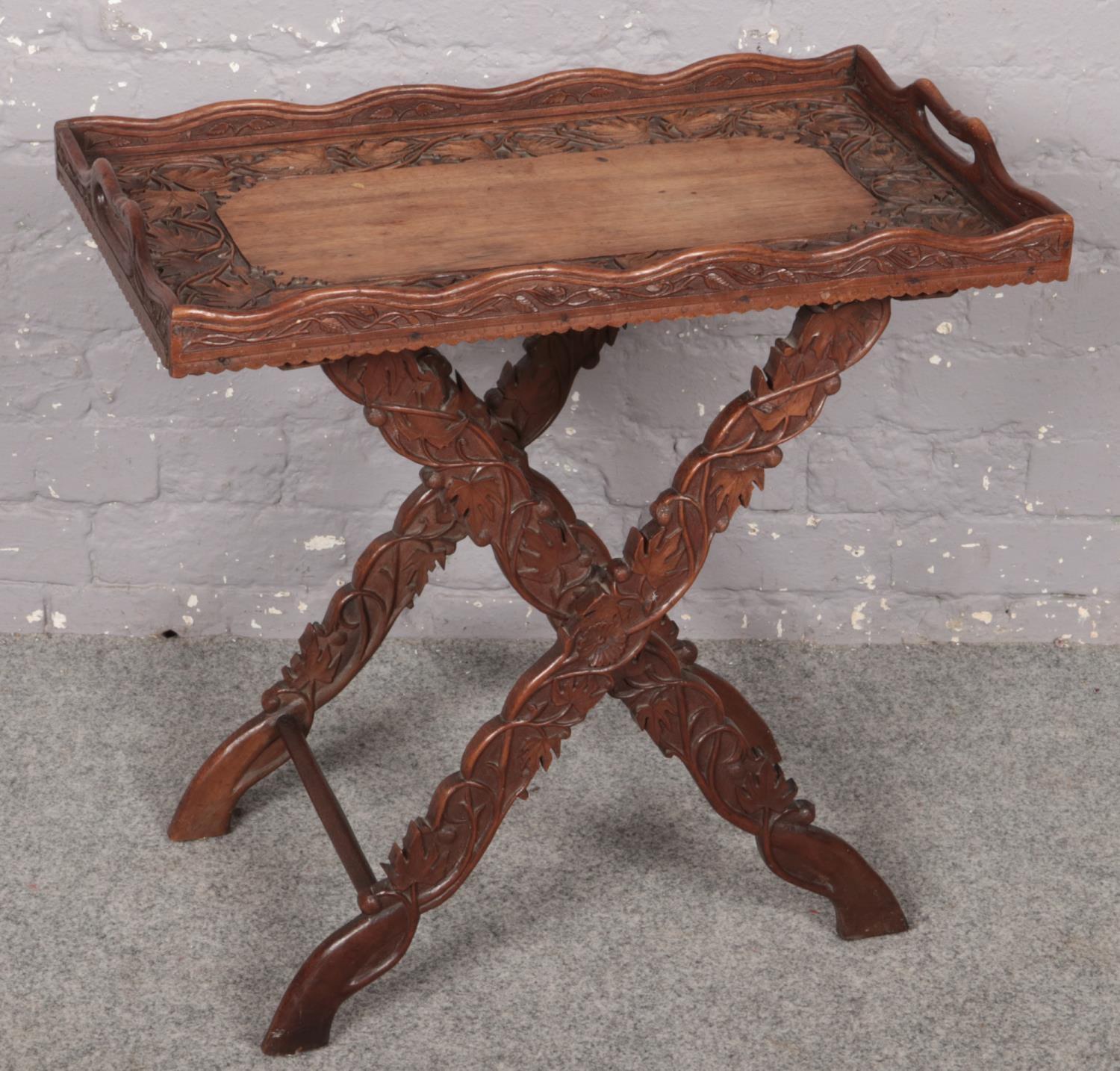 An ornate carved oak tray on stand decorated with leaves. (Total height 65cm, Tray size 68cm x