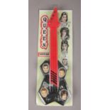 A Queen plastic guitar, in packaging. Guitar 42cm.