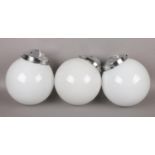 Three opaque glass globe ceiling lights with chrome fittings.