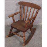 An oak spindle back child's rocking chair. Wood badly damaged to one of the front legs.
