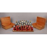 Hand carved and painted wooden chess set and board, together with two wooden storage boxes. Board