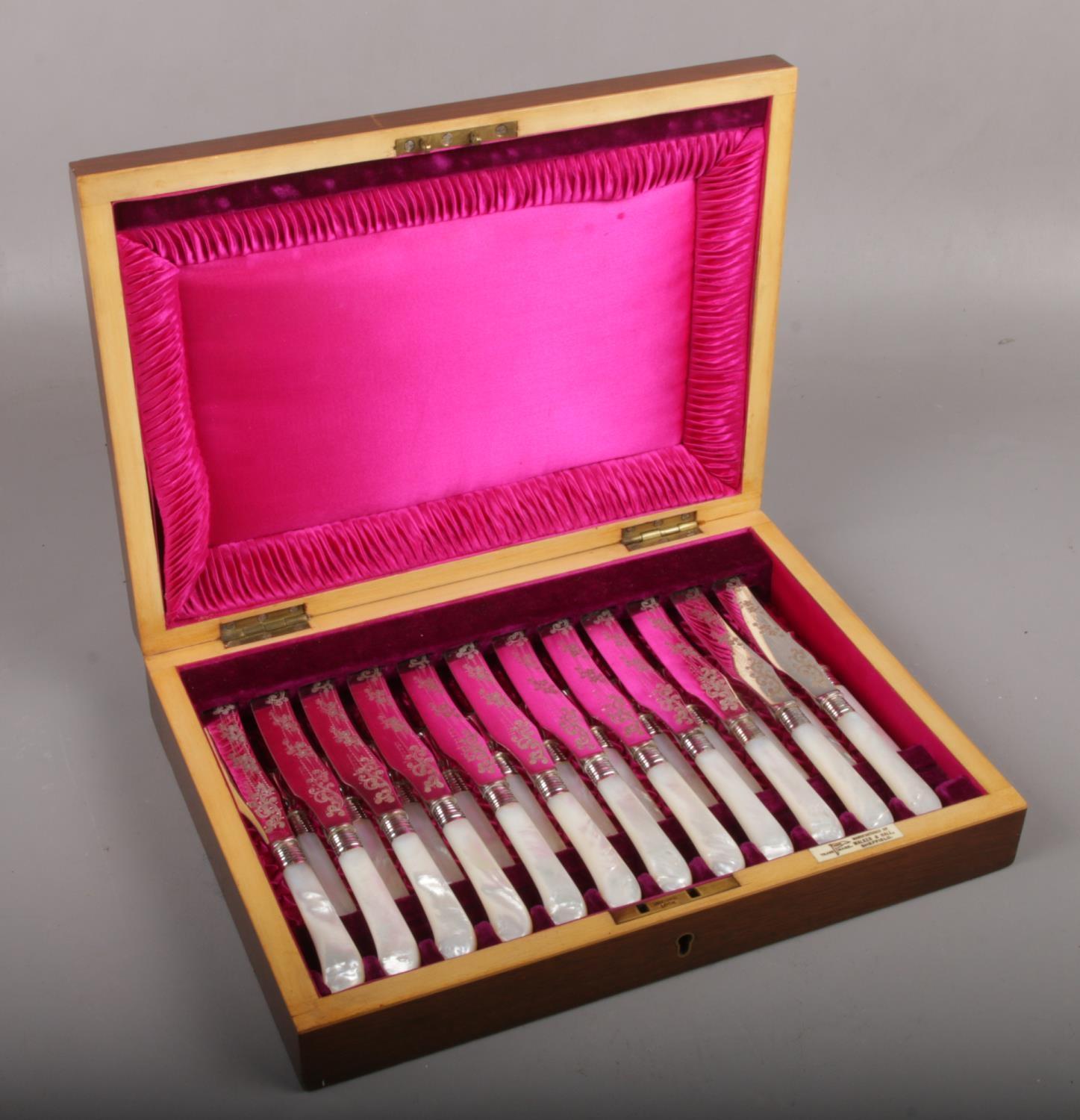 A mahogany cased set of twelve Walker & Hall mother of pearl handled dessert knives and forks.