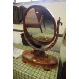 Victorian figured mahogany oval toilet mirror, with scrolled leaf finial uprights on oval platform