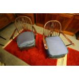 Pair of Ercol dark elm finish low armchairs with oval pierced splats, retaining labels to reverse