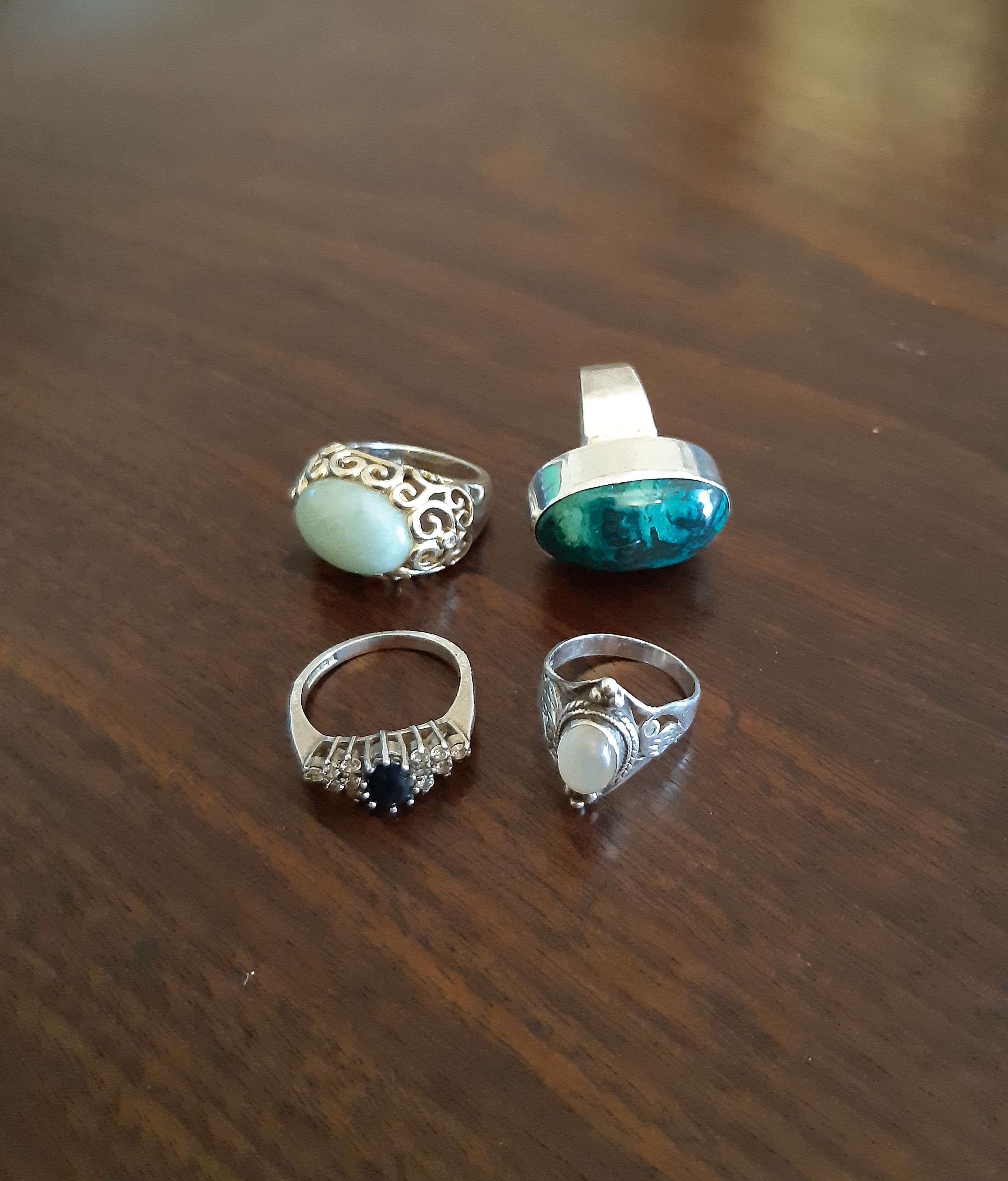 Four silver rings, variously set with moonstone, malachite and other stones
