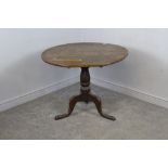 A George III oak snap-top tripod table, the circular planked top above the action and turned column,